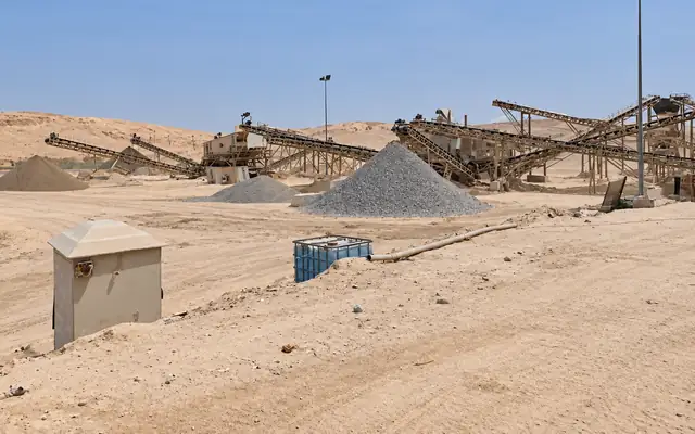 Aggregate stockpiles in different grades in front of the conveyor belts and crushing plant at a stone crushing site